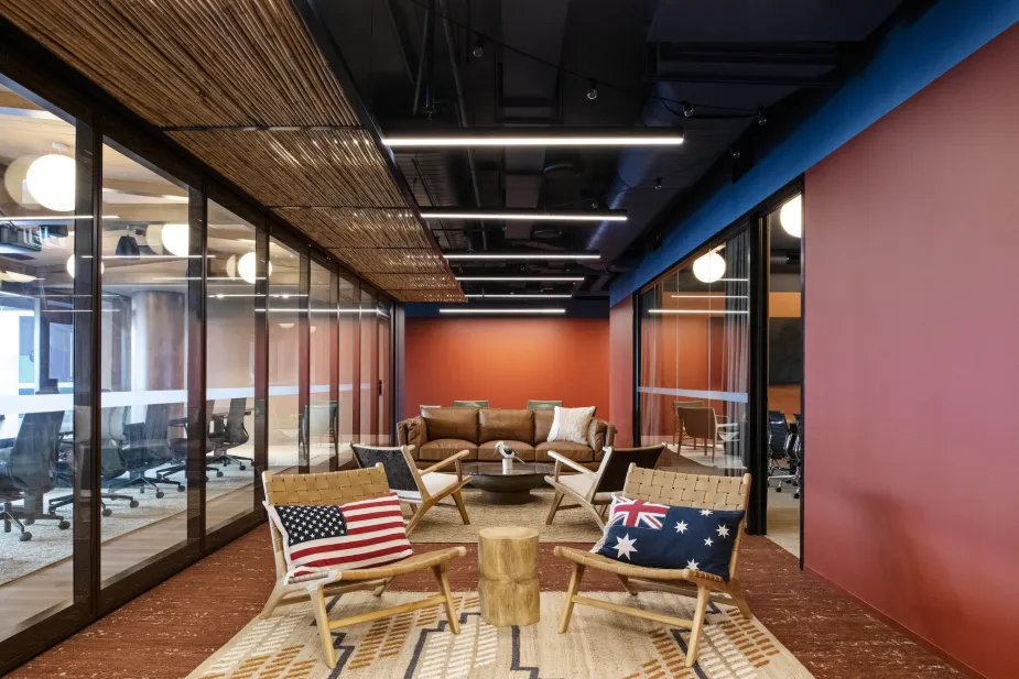 A contemporary office lounge with a warm and welcoming ambiance, featuring a seating arrangement with wooden chairs