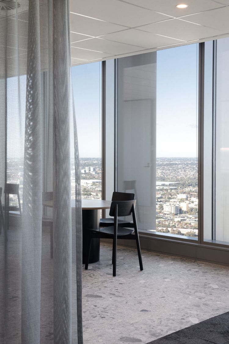 A contemporary office space featuring black wooden chairs and tables with expansive windows offering a stunning cityscape view
