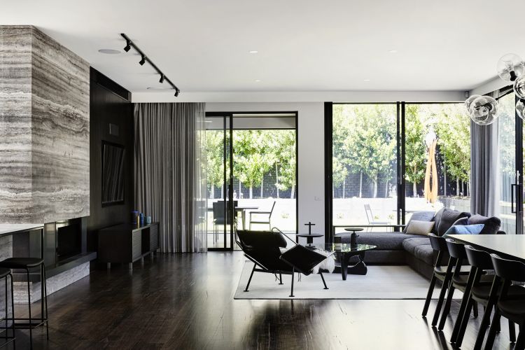 Modern and spacious living area featuring a large layered stone accent wall on the left, contrasting with a sleek dark wood built-in entertainment unit.