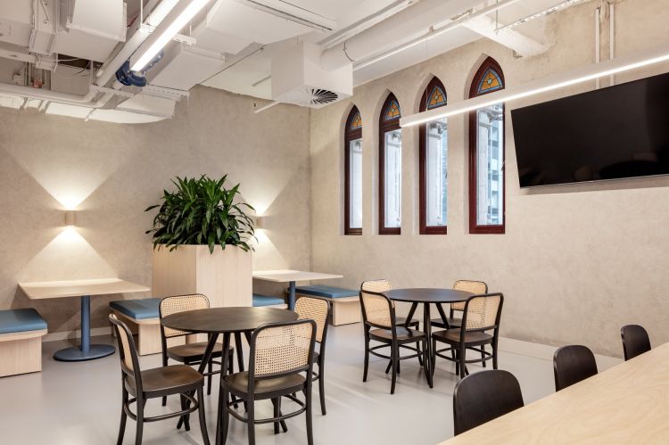 An office break area featuring a variety of seating options, including booths and round tables paired with wooden chairs.